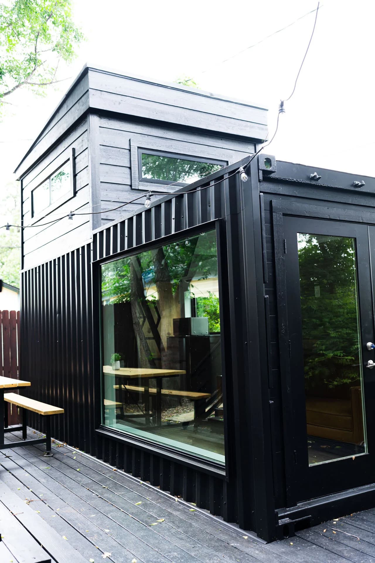 Glazed entry and elevated terrace of Domain’s dark container ADU in East Austin