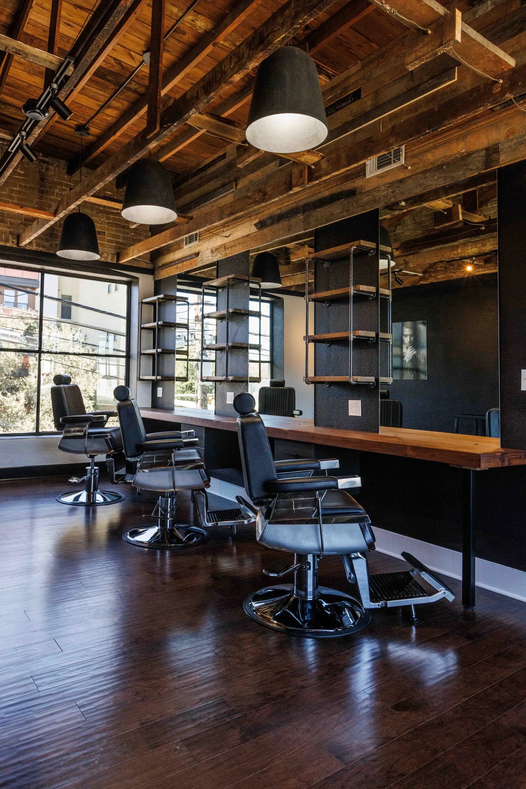 Pendant lights and a patterned ceiling above a row of barber stations