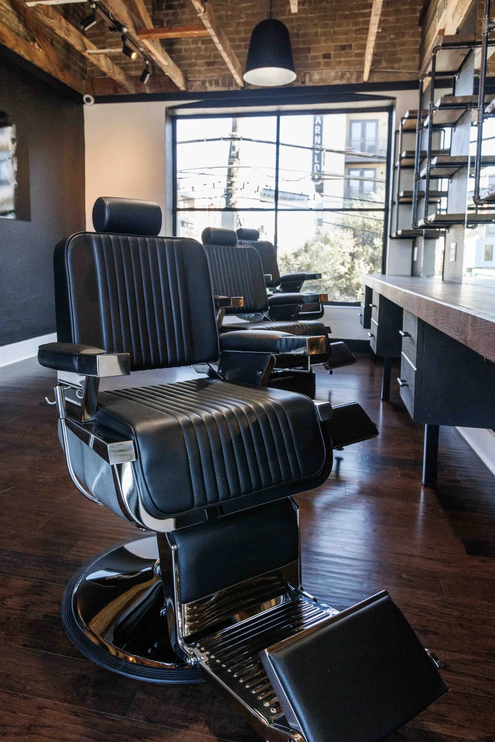 Black barber chair on a dark floor beneath track lighting