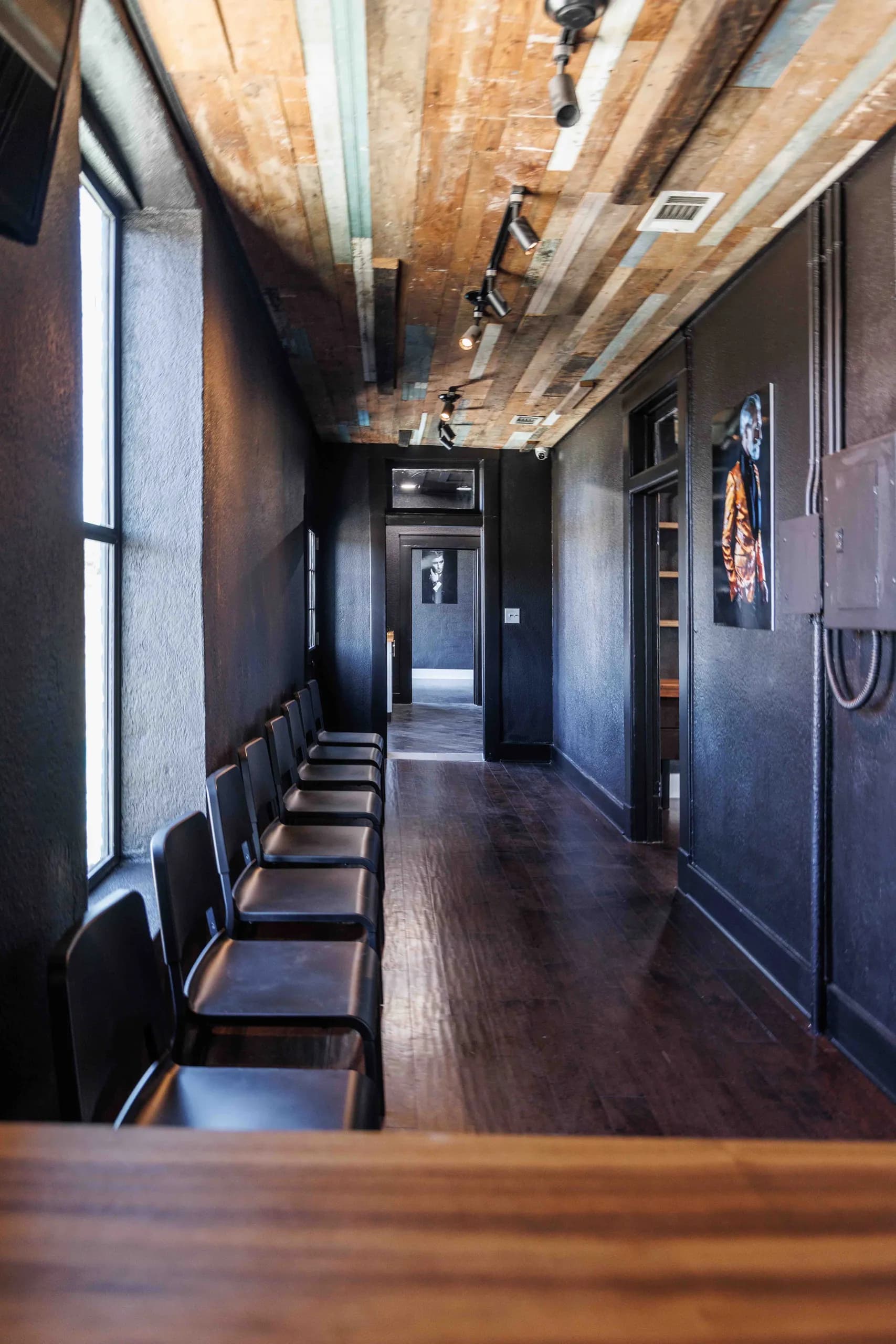 Waiting corridor with a patterned ceiling, dark walls, and a dark floor