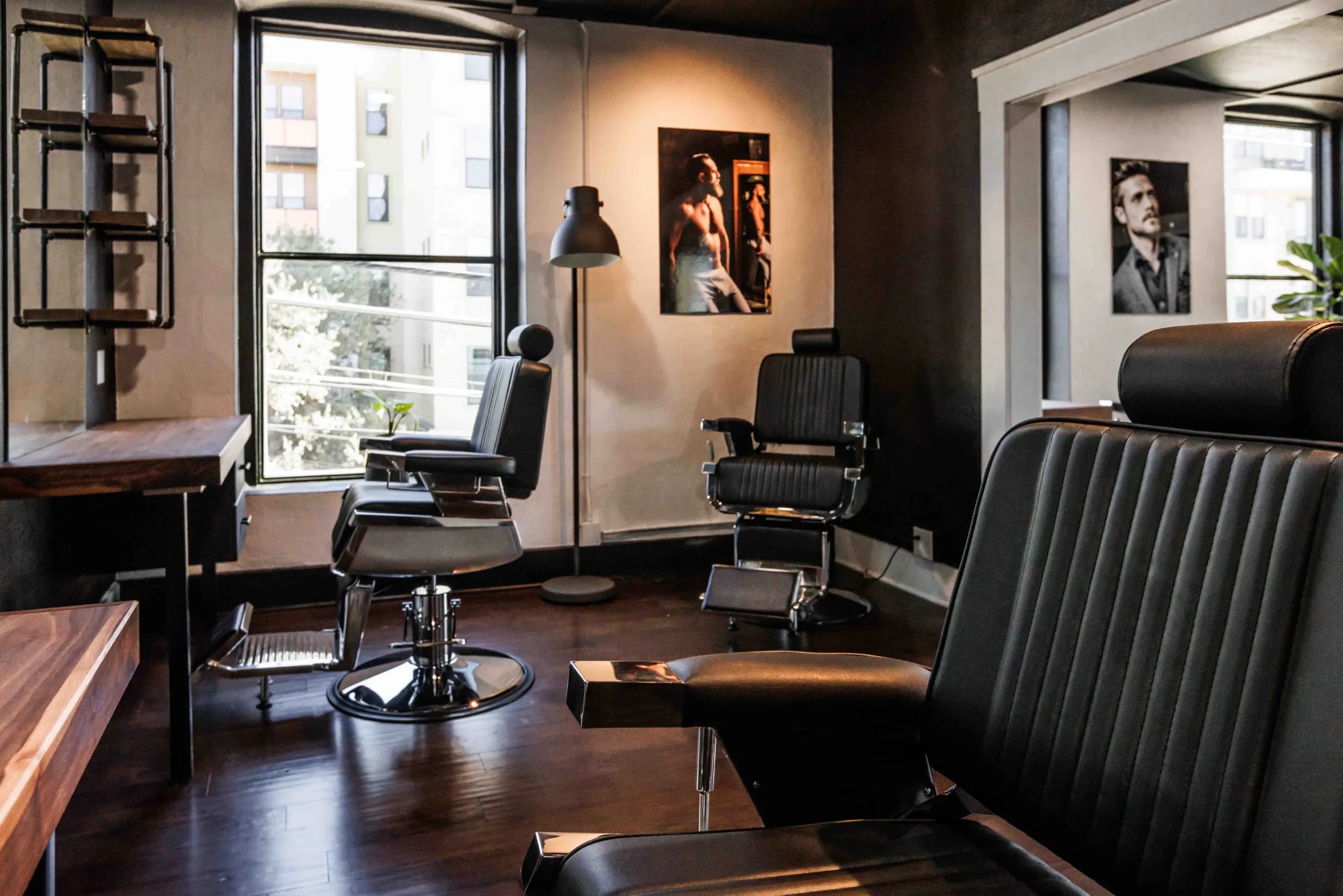 Barber chairs beside tall windows and a long workstation counter