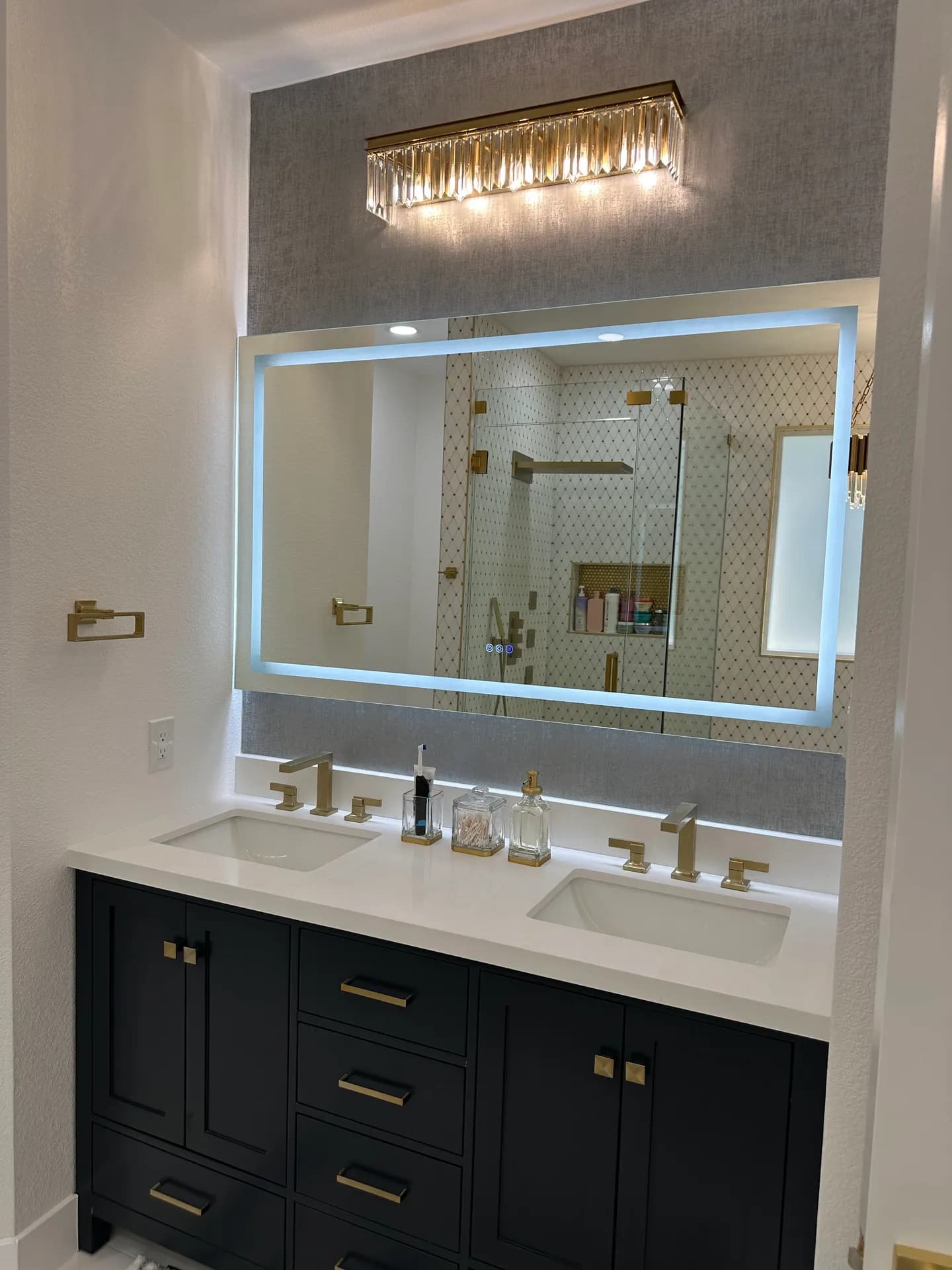 Dark double vanity with backlit mirror and gold-tone fixtures