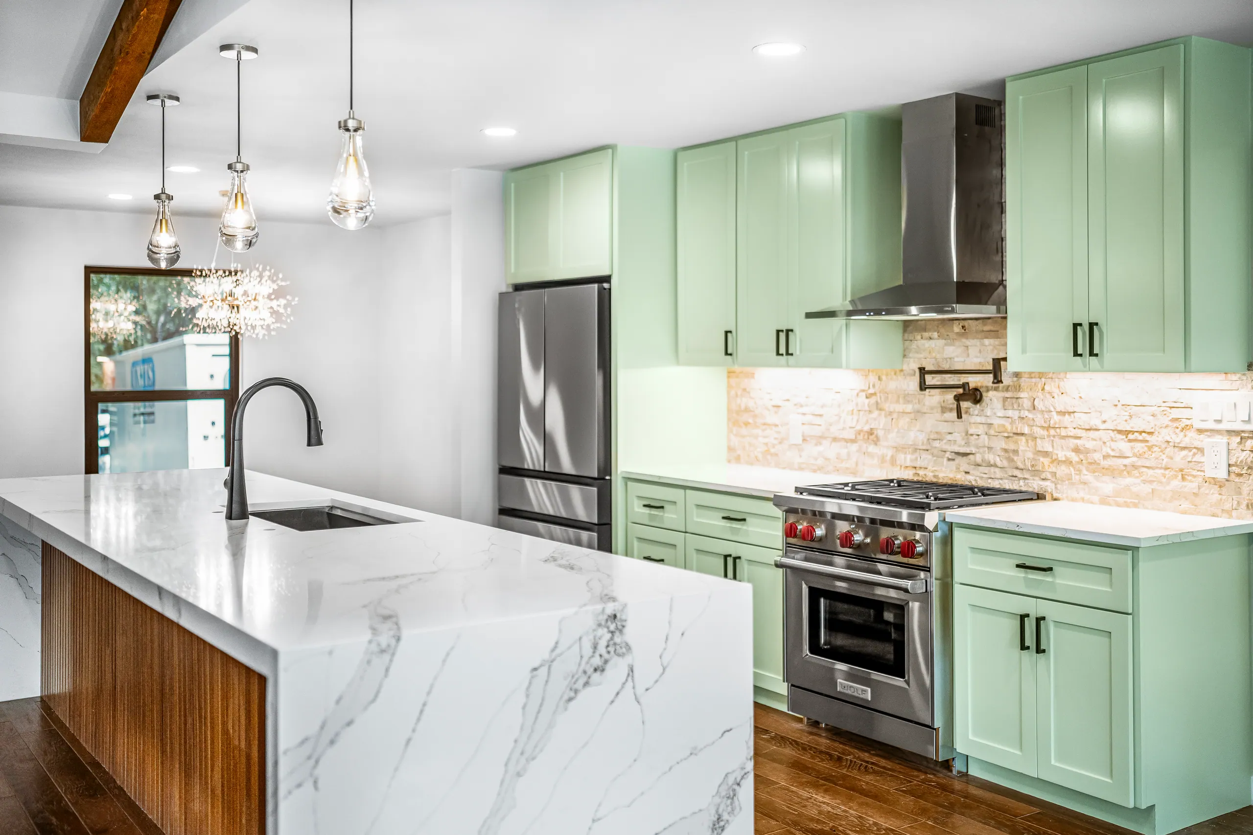 Quartz waterfall island and green kitchen cabinetry in Domain’s Northwest Austin remodel