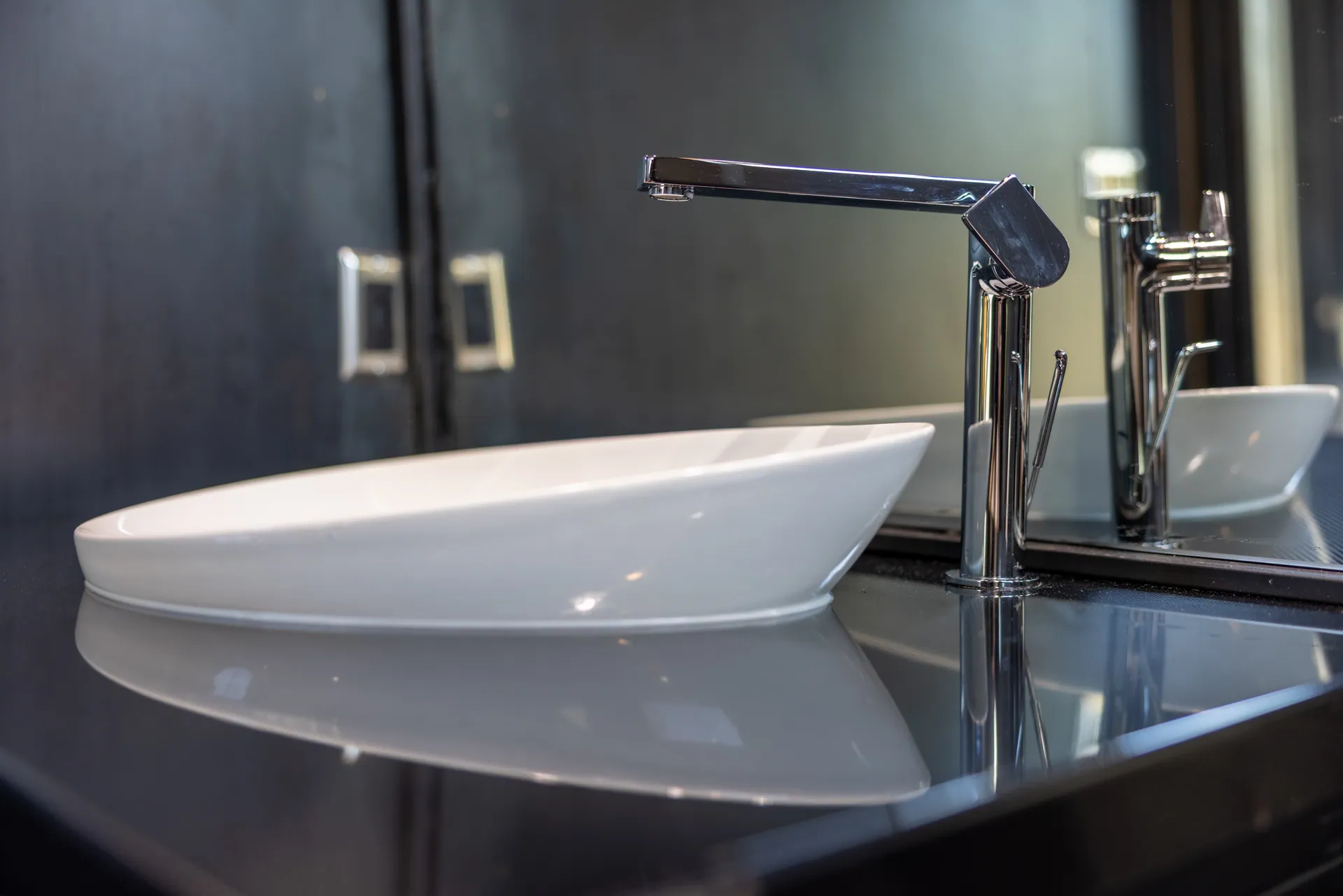 White vessel basin and chrome tap against a dark metal vanity