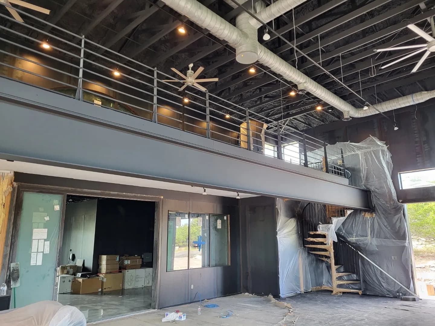The steel mezzanine and spiral stair during construction, wrapped in protective plastic