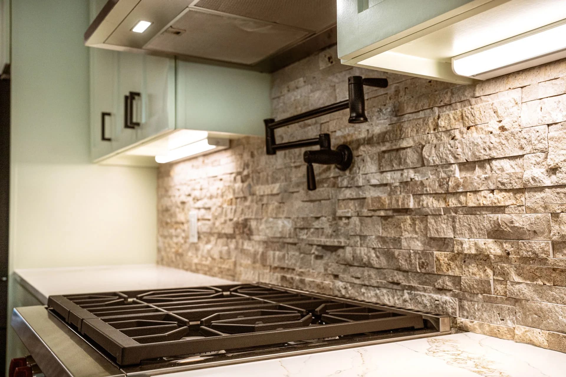 Textured stone backsplash, dark pot filler, and range in Domain’s Northwest Austin remodel