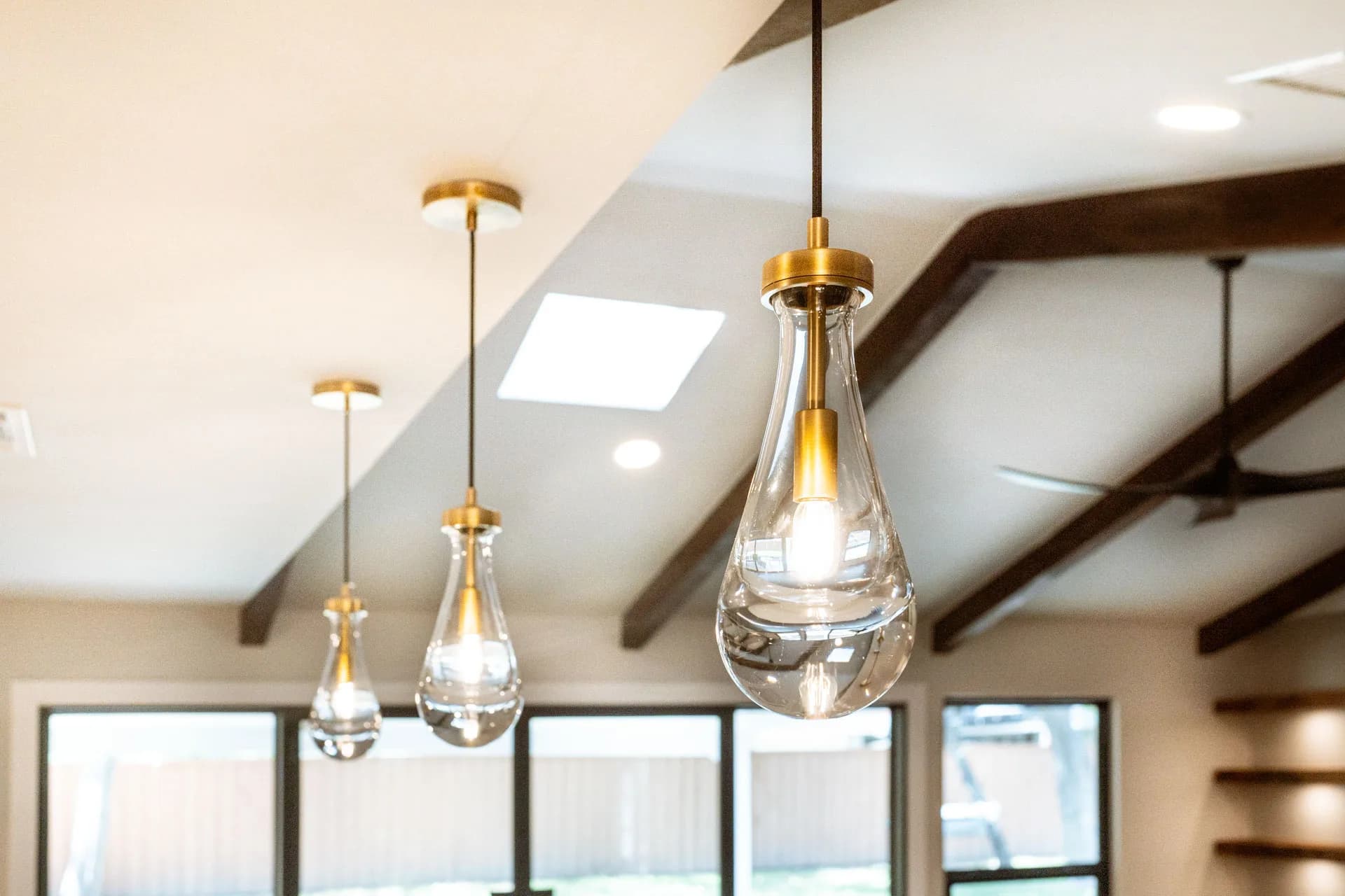 Glass pendant lighting and exposed ceiling beams in Domain’s Northwest Austin remodel