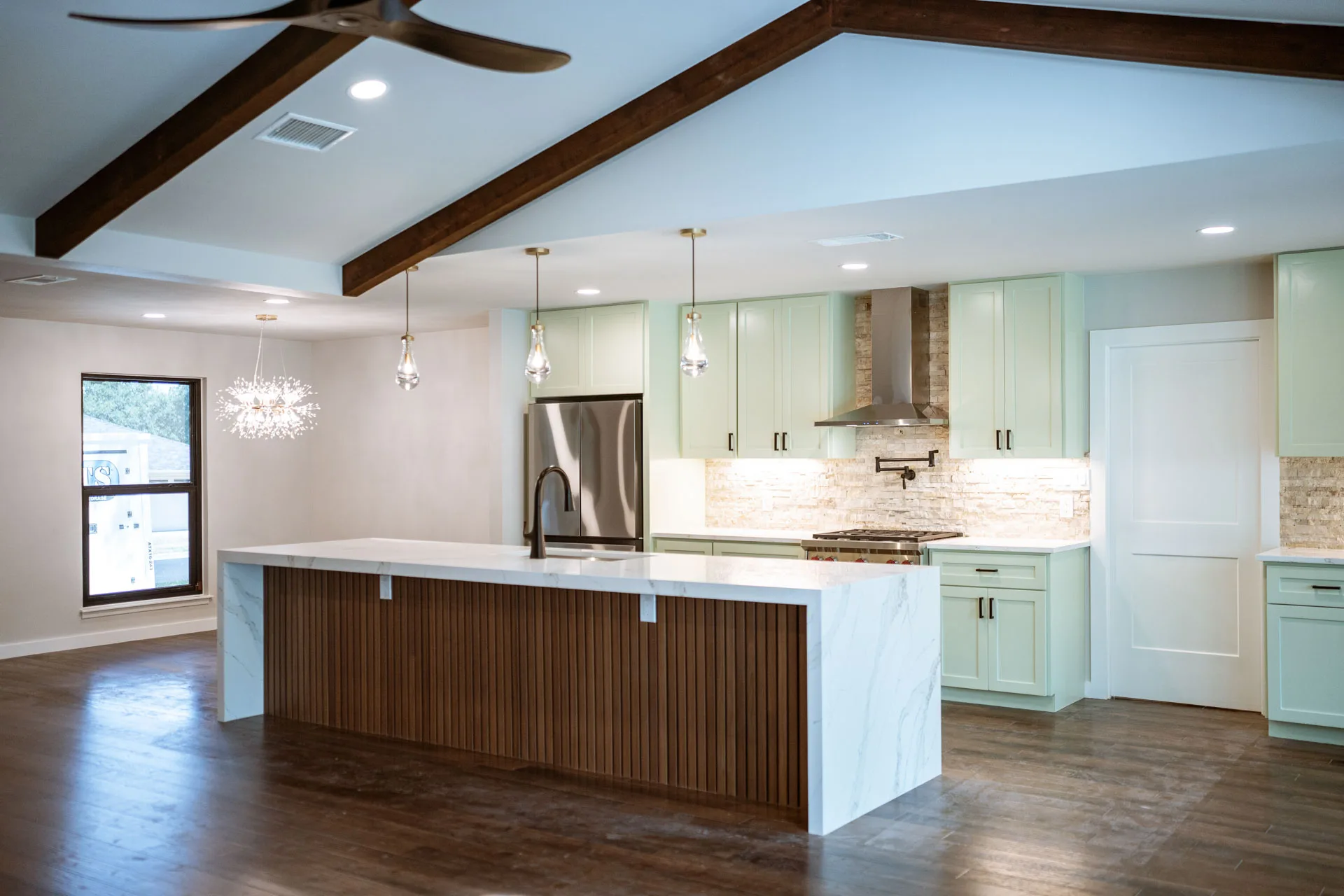 Wide view of the kitchen island, wood floors, and vaulted ceiling in Domain’s Northwest Austin remodel