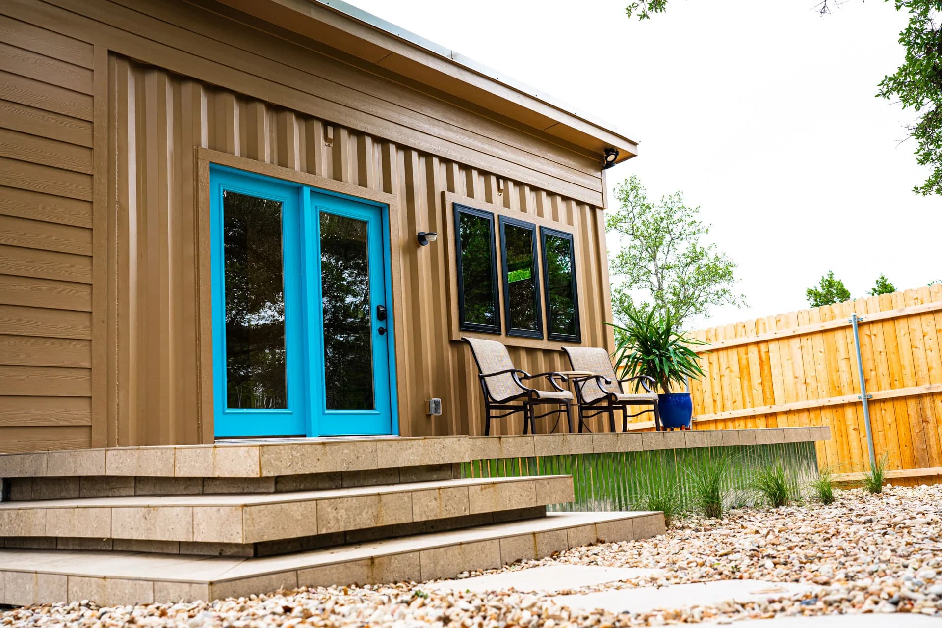 Blue entry doors and deck seating at Domain’s Tan Container ADU