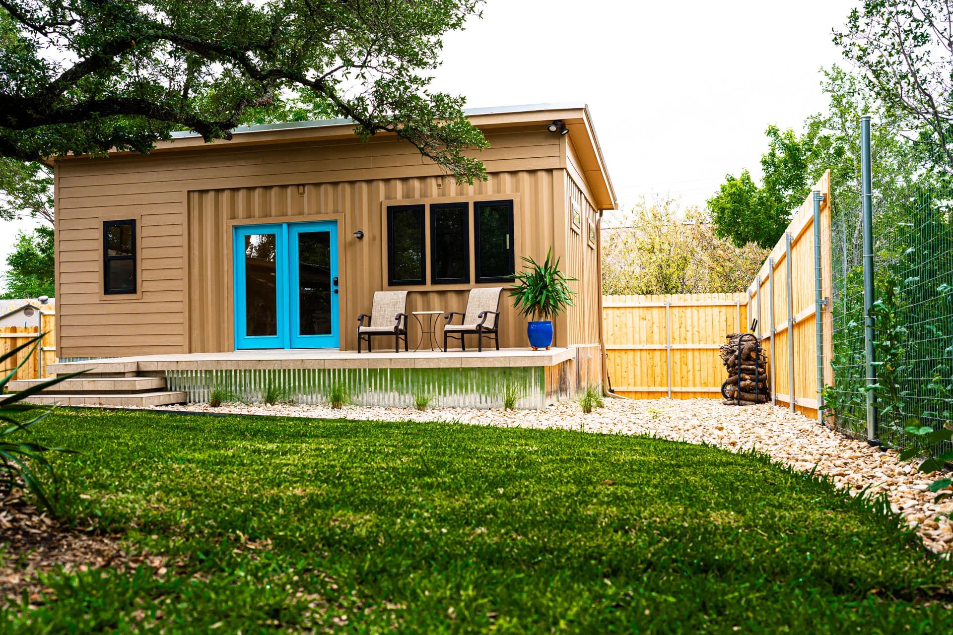 Tan Container ADU with blue entry doors and a garden-facing deck, built by Domain